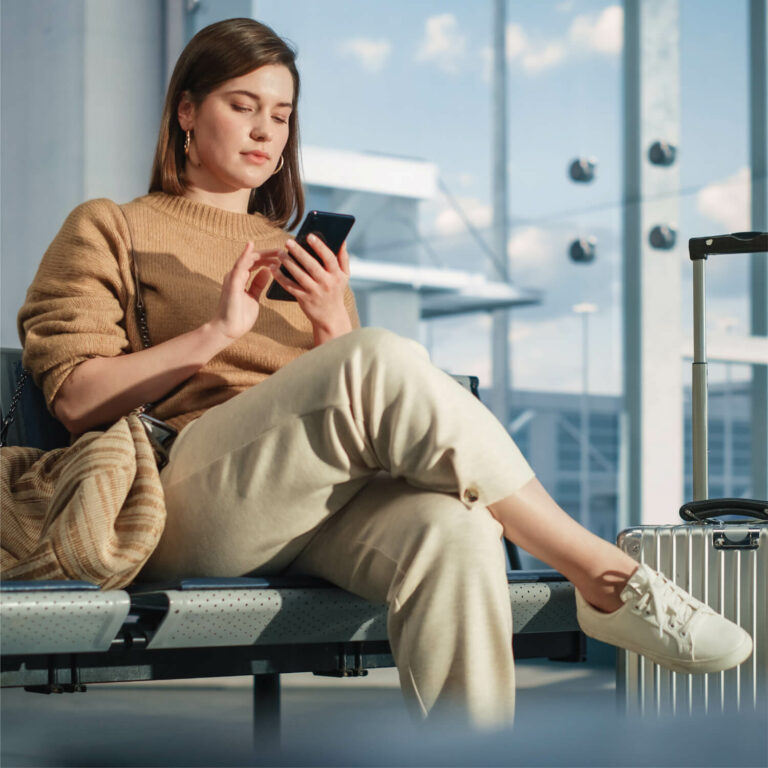 A travel passenger checking her smartphone device on an airport.